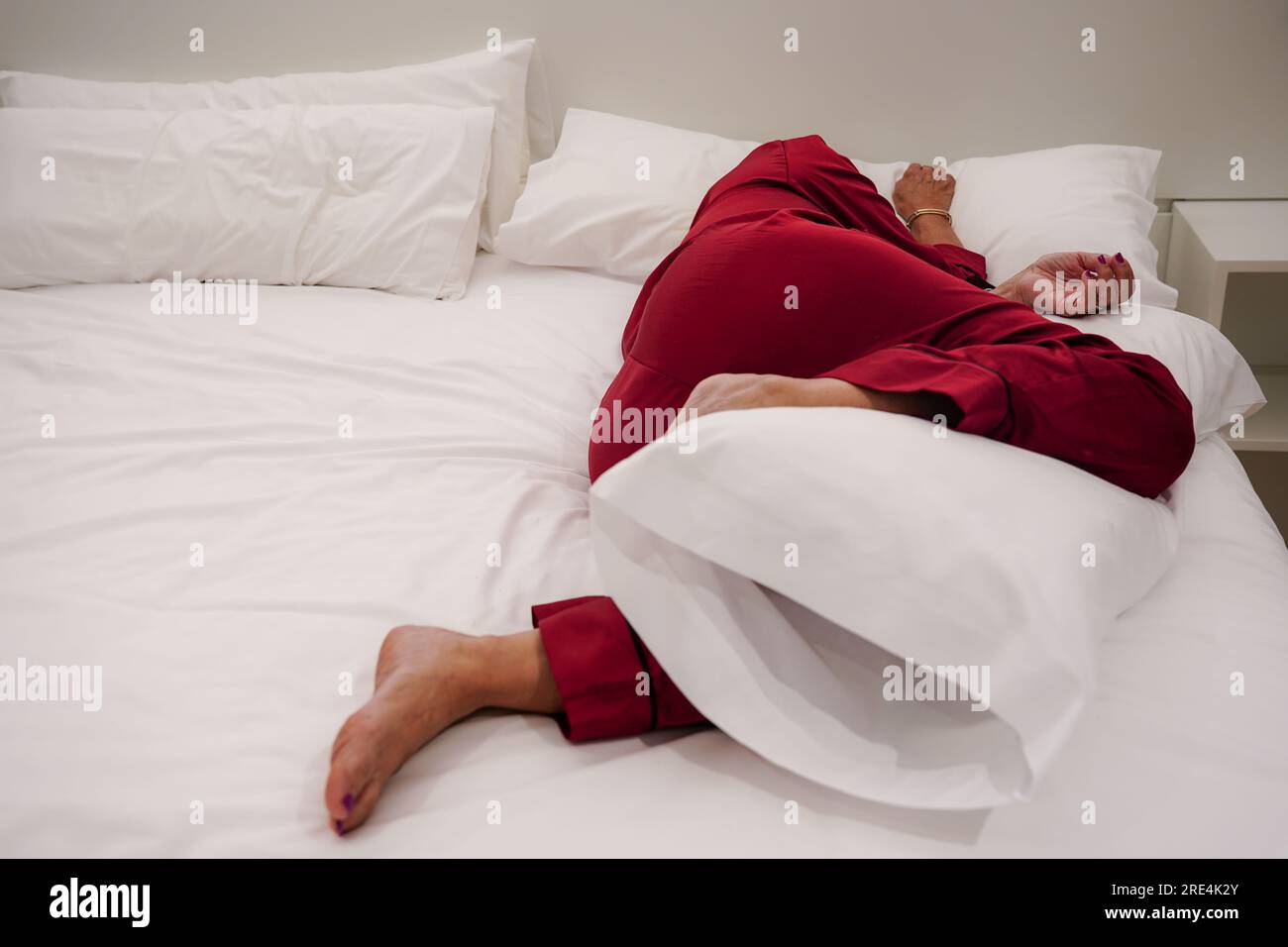 Irriconoscibile donna anziana esausta sdraiata sul letto soffre di mal di testa o emicrania, sensazione di malessere, insonnia, mancanza di sonno. Mancanza di o Foto Stock