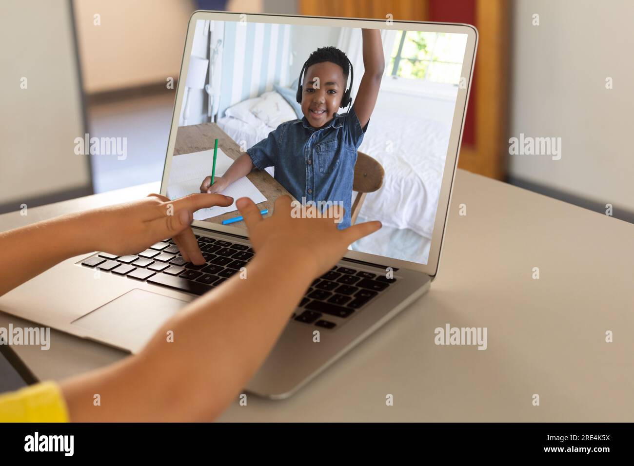 Sezione centrale di un ragazzo che usa un computer portatile mentre sta effettuando una videochiamata con un ragazzo afro-americano a casa Foto Stock