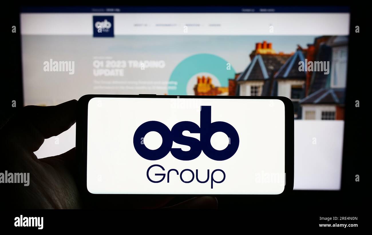 Persona che possiede uno smartphone con il logo della società finanziaria britannica OSB Group plc sullo schermo davanti al sito Web. Concentrarsi sul display del telefono. Foto Stock
