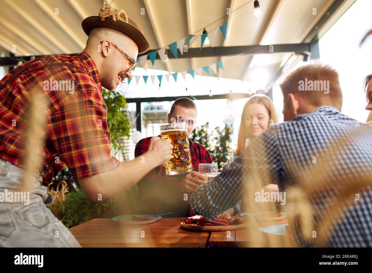 Giovani deliziosi, amici che si incontrano al pub in una giornata di sole, bevono birra lager, festeggiano festival, si divertono Foto Stock