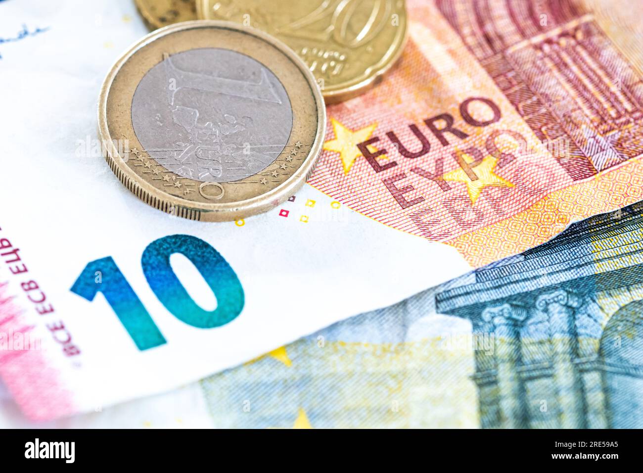 Contante in euro, banconote da 10 e 5 euro con 1 moneta in euro come sfondo per temi quali economia, finanza, risparmio e investimenti. Foto Stock