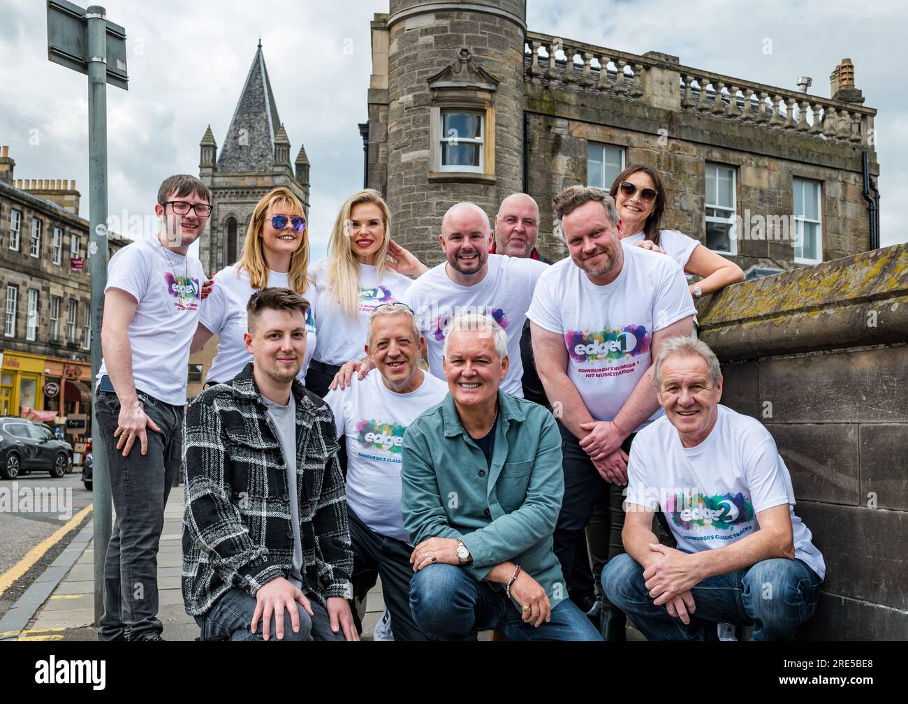 Stockbridge, Edimburgo, Scozia, Regno Unito, 25 luglio 2023. Lancio di Edge 2 radio Station: DJ Jay Crawford, uno dei DJ radiofonici più amati di Edimburgo, ha rilevato la stazione DAB MIX 1 per creare Edge 2, la nuova stazione locale di Edimburgo che offre la migliore musica degli ultimi 50 anni e ha iniziato a trasmettere questo mese. Nella foto: Jay Crawford con molti membri del suo team tra cui Sam Hinks, Mark Martin, Micky Gavin, Vikki Heaney e Veronika Walker (davanti). Crediti: Sally Anderson/Alamy Live News Foto Stock