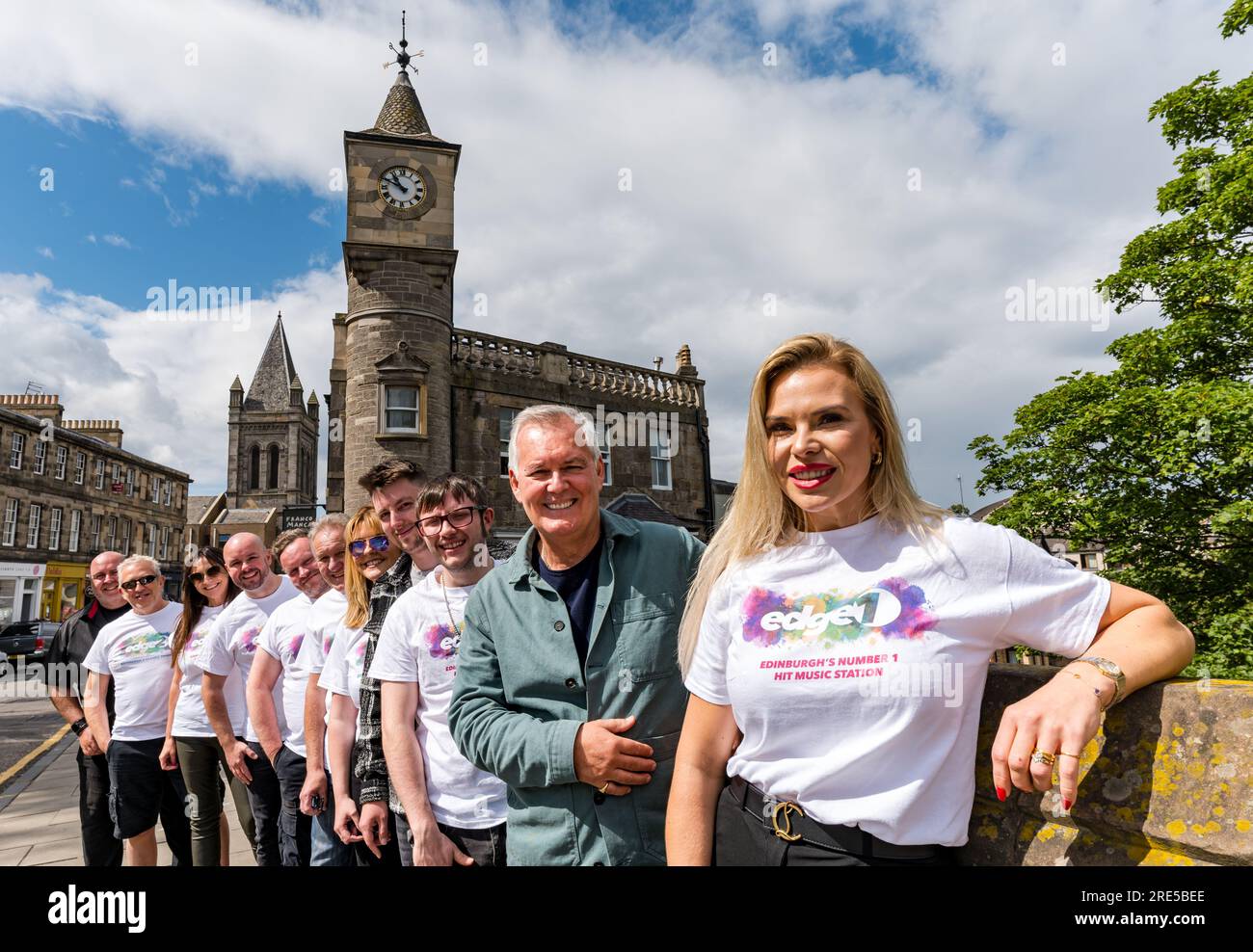 Stockbridge, Edimburgo, Scozia, Regno Unito, 25 luglio 2023. Lancio di Edge 2 radio Station: DJ Jay Crawford, uno dei DJ radiofonici più amati di Edimburgo, ha rilevato la stazione DAB MIX 1 per creare Edge 2, la nuova stazione locale di Edimburgo che offre la migliore musica degli ultimi 50 anni e ha iniziato a trasmettere questo mese. Nella foto: Jay Crawford con molti membri del suo team tra cui Sam Hinks, Mark Martin, Micky Gavin, Vikki Heaney e Veronika Walker (davanti). Crediti: Sally Anderson/Alamy Live News Foto Stock