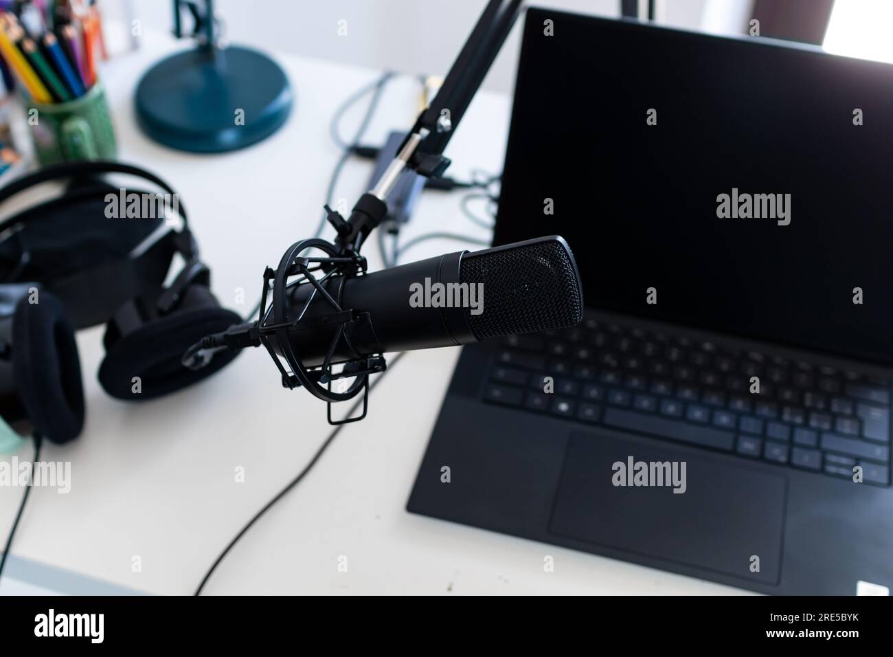 Microfono, laptop e cuffie per sessioni di streaming live a casa. Strumenti per attività di coinvolgimento del pubblico digitale, come podcast, webinar, social media Foto Stock