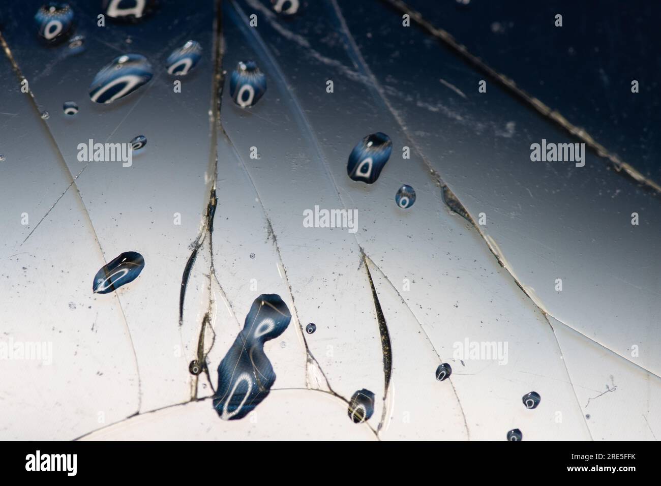 Vetro incrinato con gocce d'acqua. Fondo in vetro rotto con goccia d'acqua e riflesso sulla superficie. Sfondo del concetto di freno Foto Stock