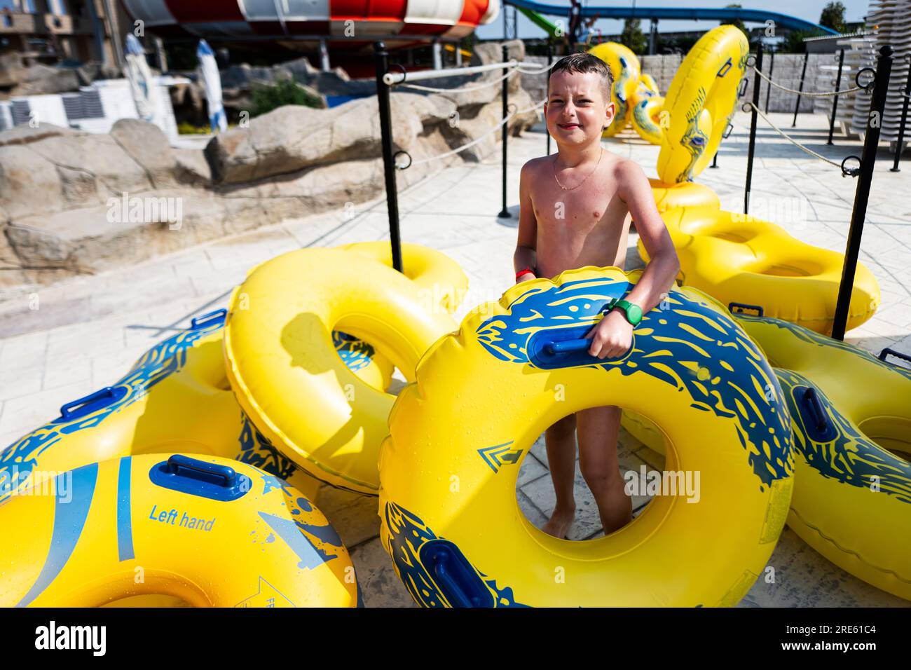 Ragazzo con anelli gonfiabili nel parco acquatico in una giornata di sole. Foto Stock