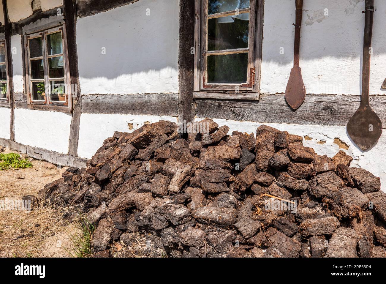 Pila di torba secca per il carburante all'esterno di un vecchio casale in legno a Kluki, villaggio di pescatori prussiano sulla costa baltica in Polonia. Riscaldamento globale Foto Stock