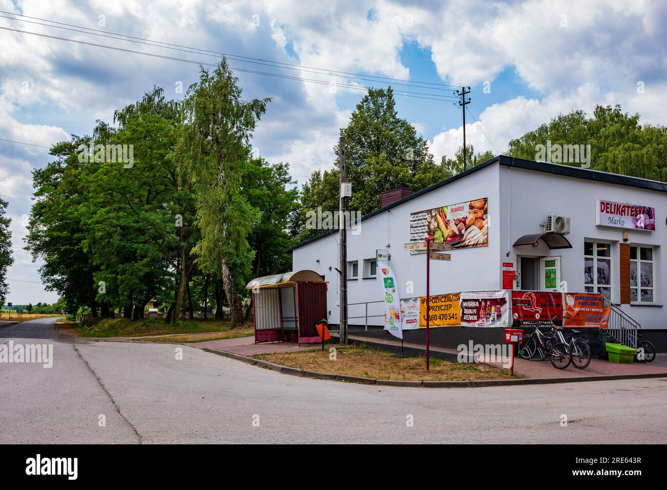 Negozio polacco del villaggio, con cassetta postale e biciclette dei clienti all'esterno, comunità rurale, paesaggio di campagna polacco, stile di vita del villaggio. Rosso Foto Stock