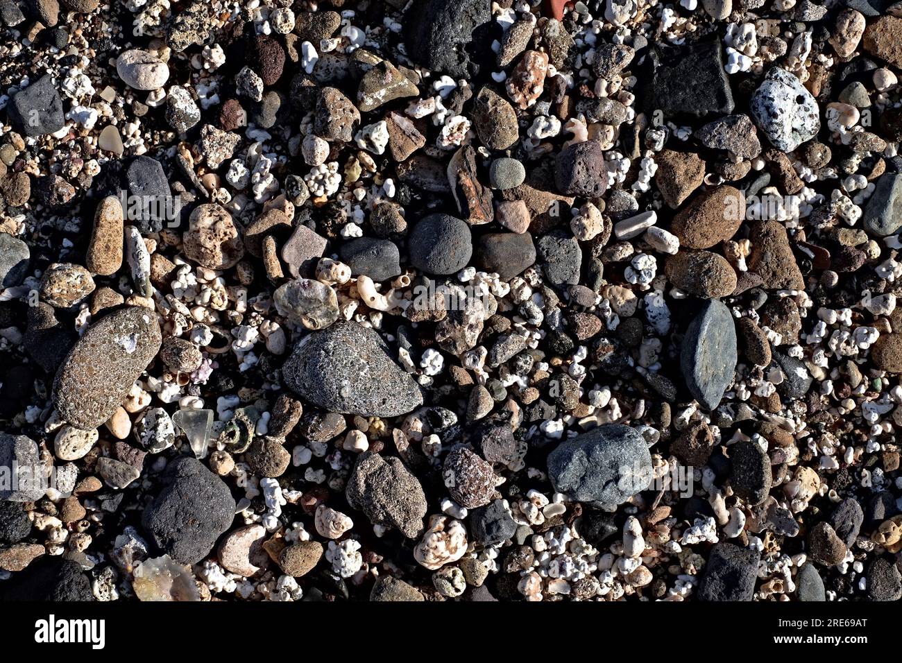 Motivo di pietre da spiaggia assortite bianche, grigie e nere, immagine a basso contrasto e bassa saturazione. Foto Stock
