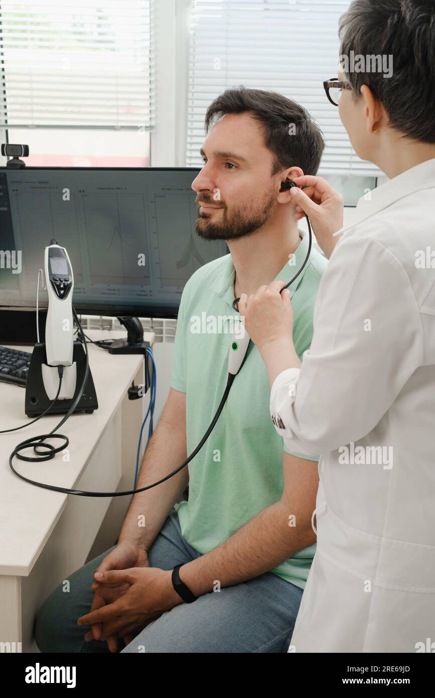 L'uomo ha un appuntamento alla clinica, controlla l'udito. Medico audiologo consulente presso una clinica di riabilitazione dell'udito per selezionare il dispositivo digitale per il centro Foto Stock