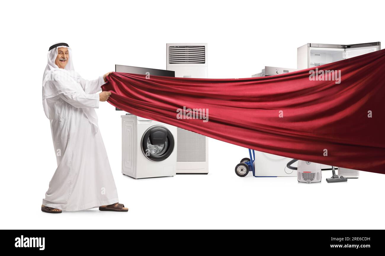 Uomo arabo in abiti tradizionali che tira un pezzo di stoffa rosso davanti a apparecchi elettrici isolati su sfondo bianco Foto Stock