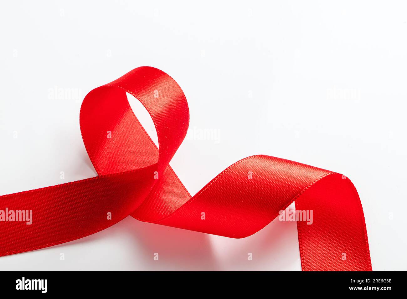 Nastro di seta rossa per l'imballaggio dei regali su sfondo bianco. Ricci di nastro decorativo per le vacanze. Elemento per il design. Foto Stock