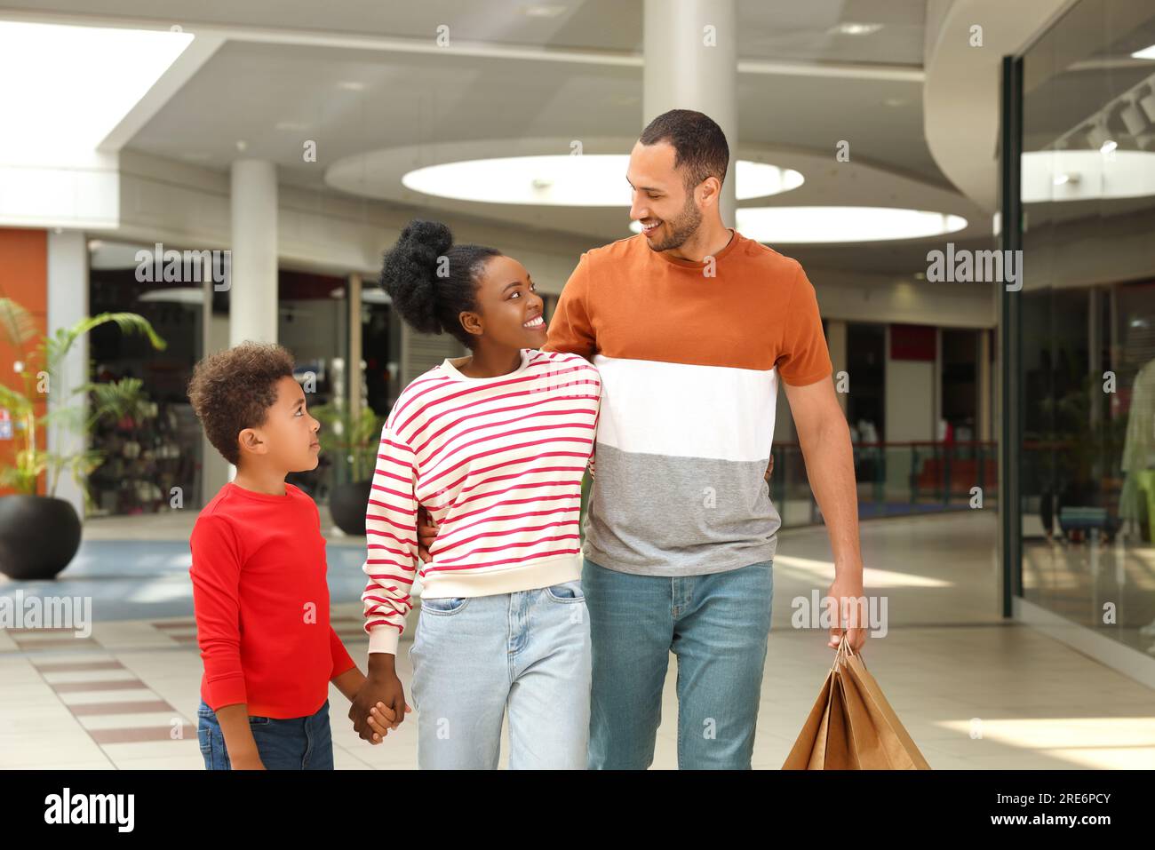 Shopping per famiglie. Genitori e figlio felici con gli acquisti al centro commerciale Foto Stock