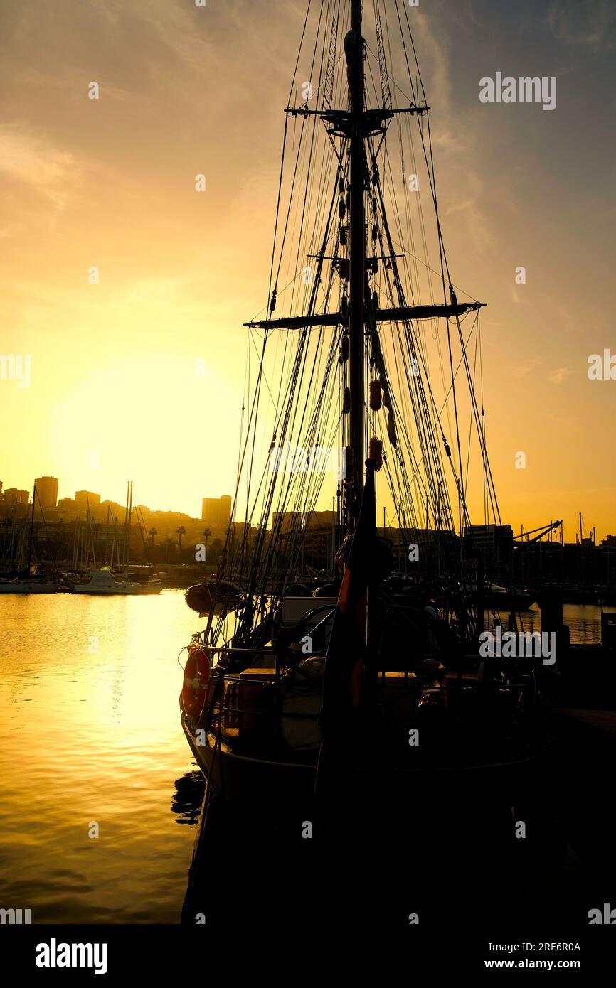 Sagoma di una nave a vela al tramonto. Una classica nave romantica nel suo porto di casa. Foto Stock