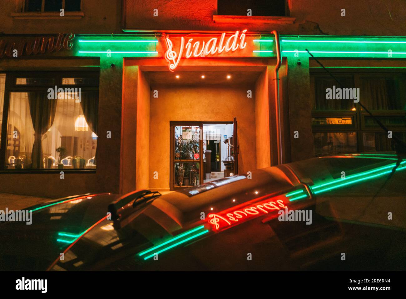 La brillante segnaletica al neon di Vivaldi si riflette sul tetto di un'auto nella città vecchia di Plovdiv, Bulgaria Foto Stock
