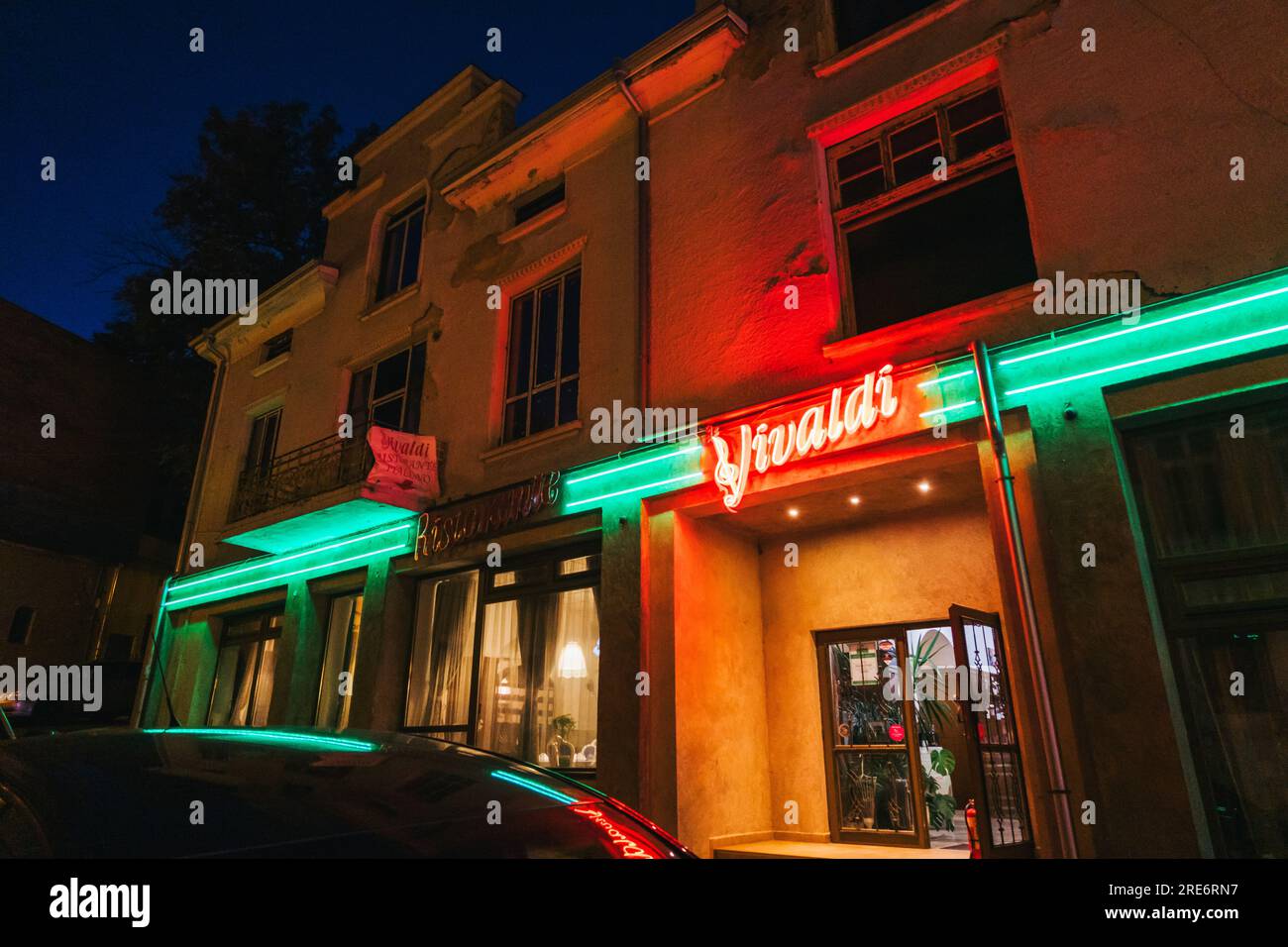 La luminosa segnaletica al neon del ristorante Vivaldi illumina una strada della città vecchia a Plovdiv, Bulgaria Foto Stock