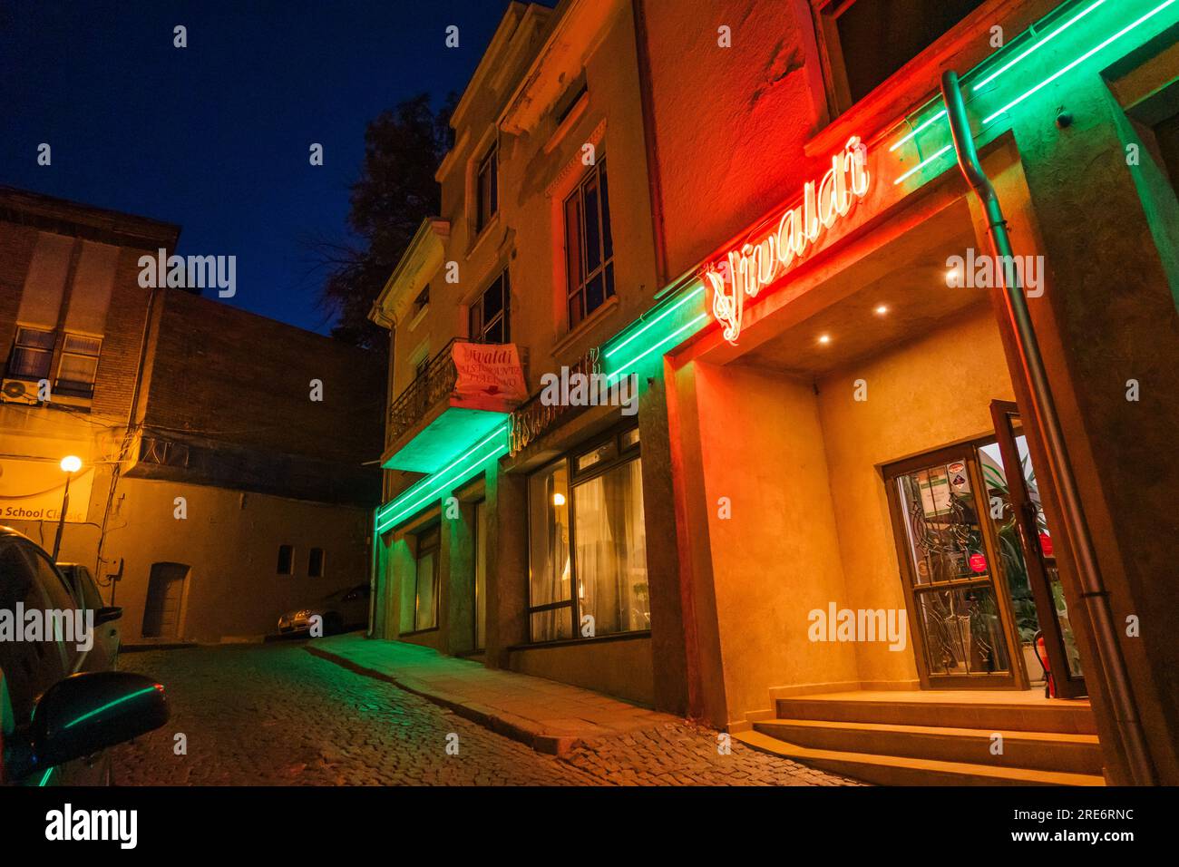 La luminosa segnaletica al neon del ristorante Vivaldi illumina una strada della città vecchia a Plovdiv, Bulgaria Foto Stock