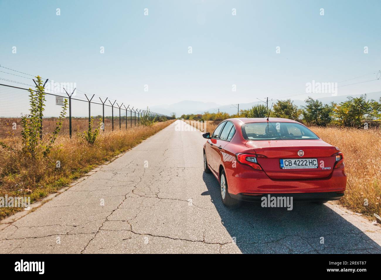 Una Fiat tipo berlina rossa parcheggiata su una strada rettilinea e vuota a Plovdiv, Bulgaria Foto Stock