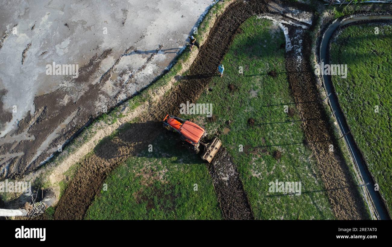 Vista aerea di un trattore in un campo che ara il terreno in preparazione alla semina. Agricoltore nel trattore che prepara terreni con coltivatore a seminativo. Foto Stock