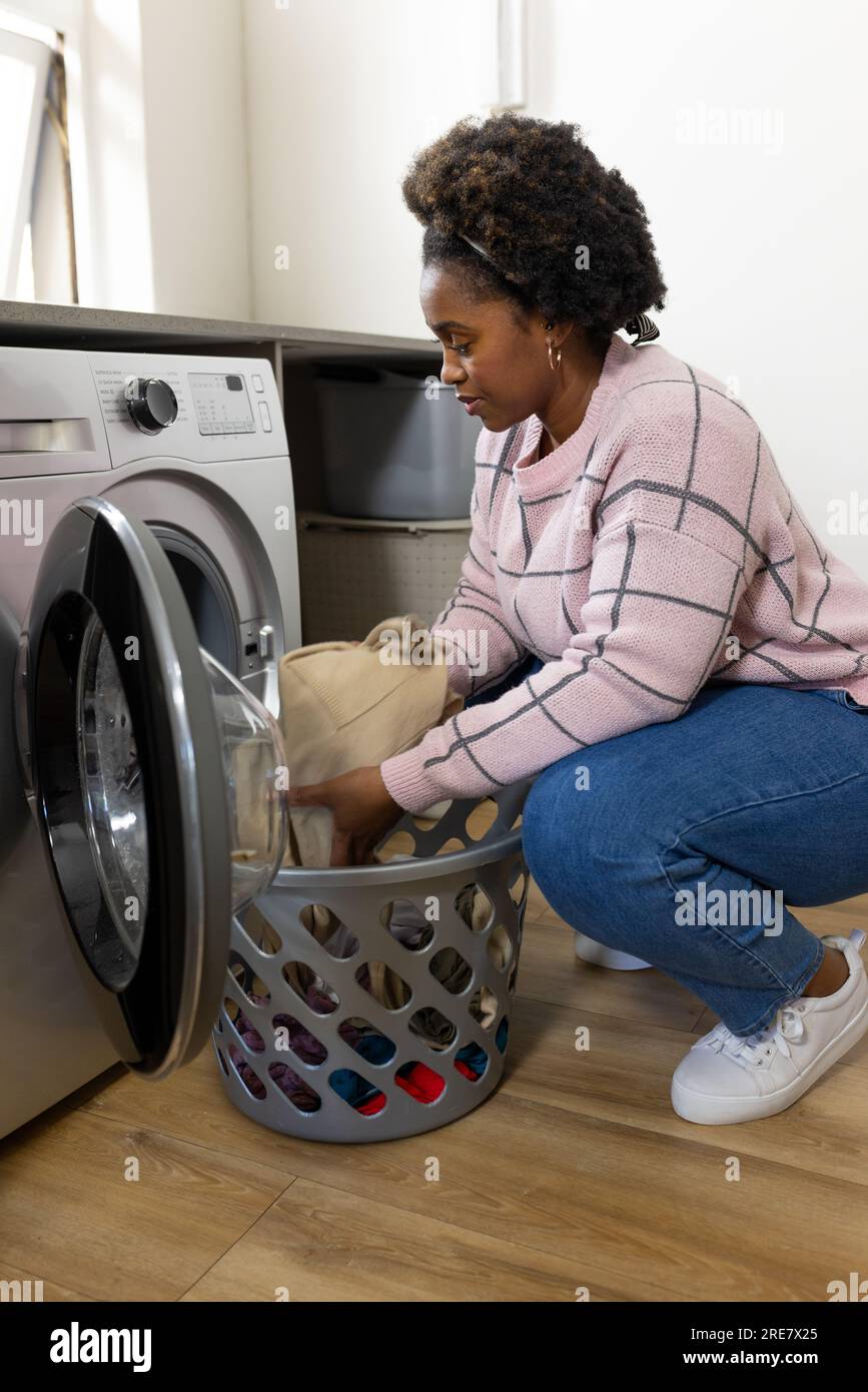 Donna afro-americana più grande che fa il bucato a casa Foto Stock