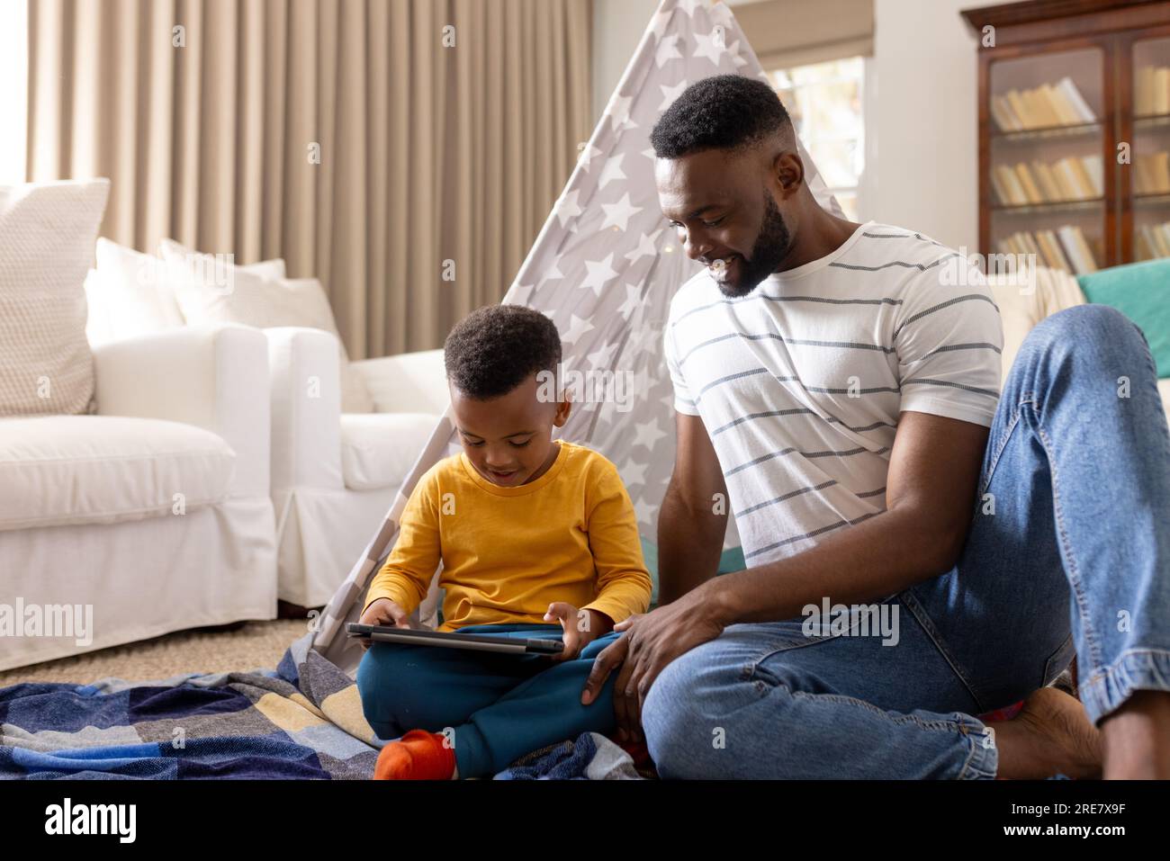Padre e figlio afroamericani felici che usano il tablet a casa Foto Stock