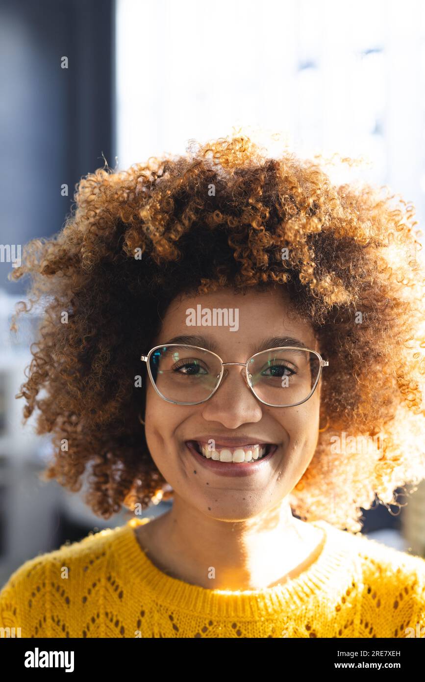 Ritratto di una donna d'affari birazziale con capelli ricci su un modello di edificio in ufficio Foto Stock