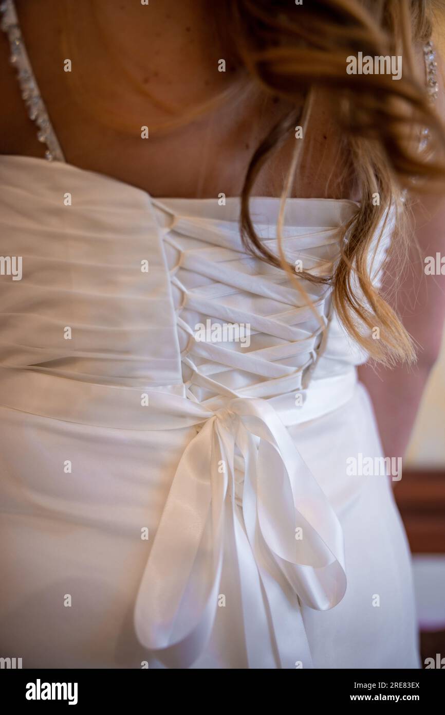 Il retro di un abito da sposa bianco. La schiena di una sposa e i suoi capelli che scorrono sul suo abito bianco. Foto di alta qualità Foto Stock