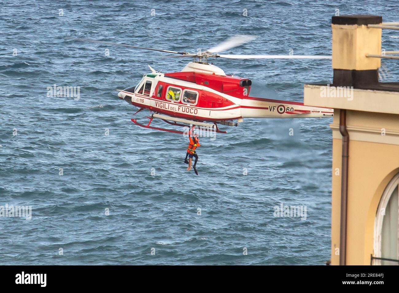 I nuotatori di salvataggio in elicottero di Vigili del fuoco assistono un gruppo di nuotatori incauti che sono stati portati via dal mare accidentato e li sollevano con l'argano sul loro elicottero. Foto Stock