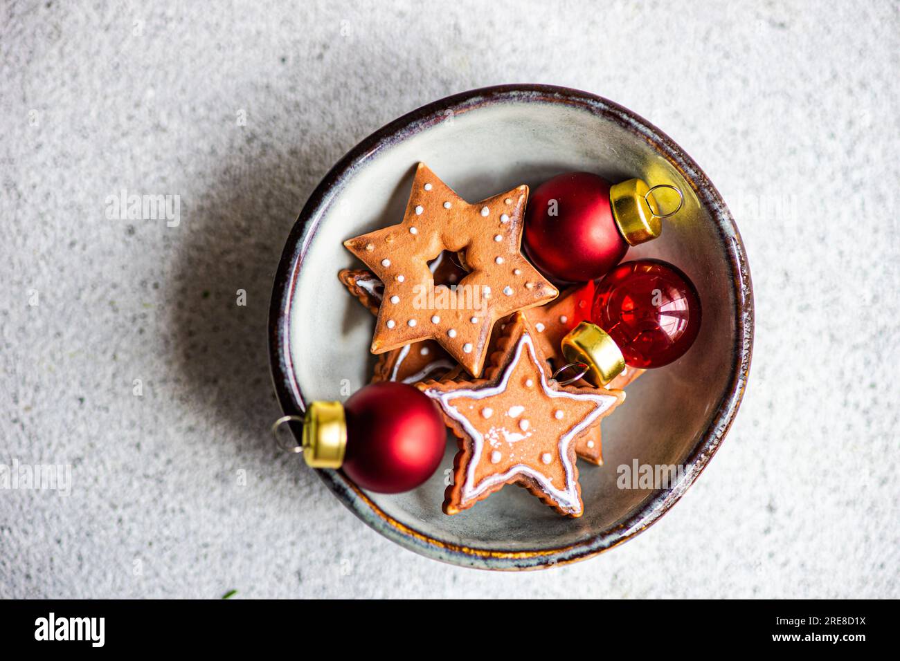 Ciotola con biscotti a forma di stella e palline decorative rosse Foto Stock