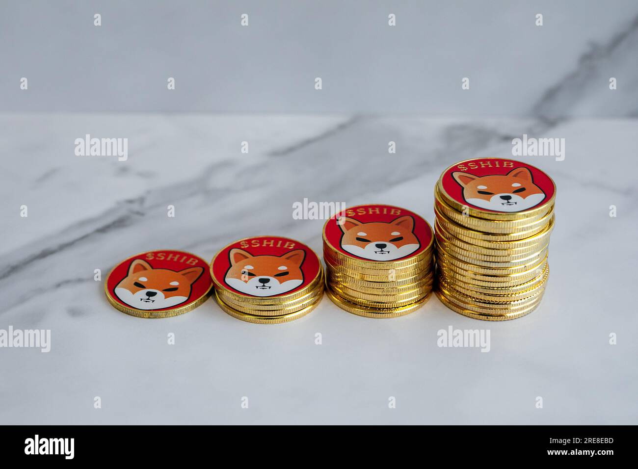 Le monete Shiba inu (SHIB) sono ordinate da piccole a grandi con uno sfondo di marmo bianco. Foto Stock