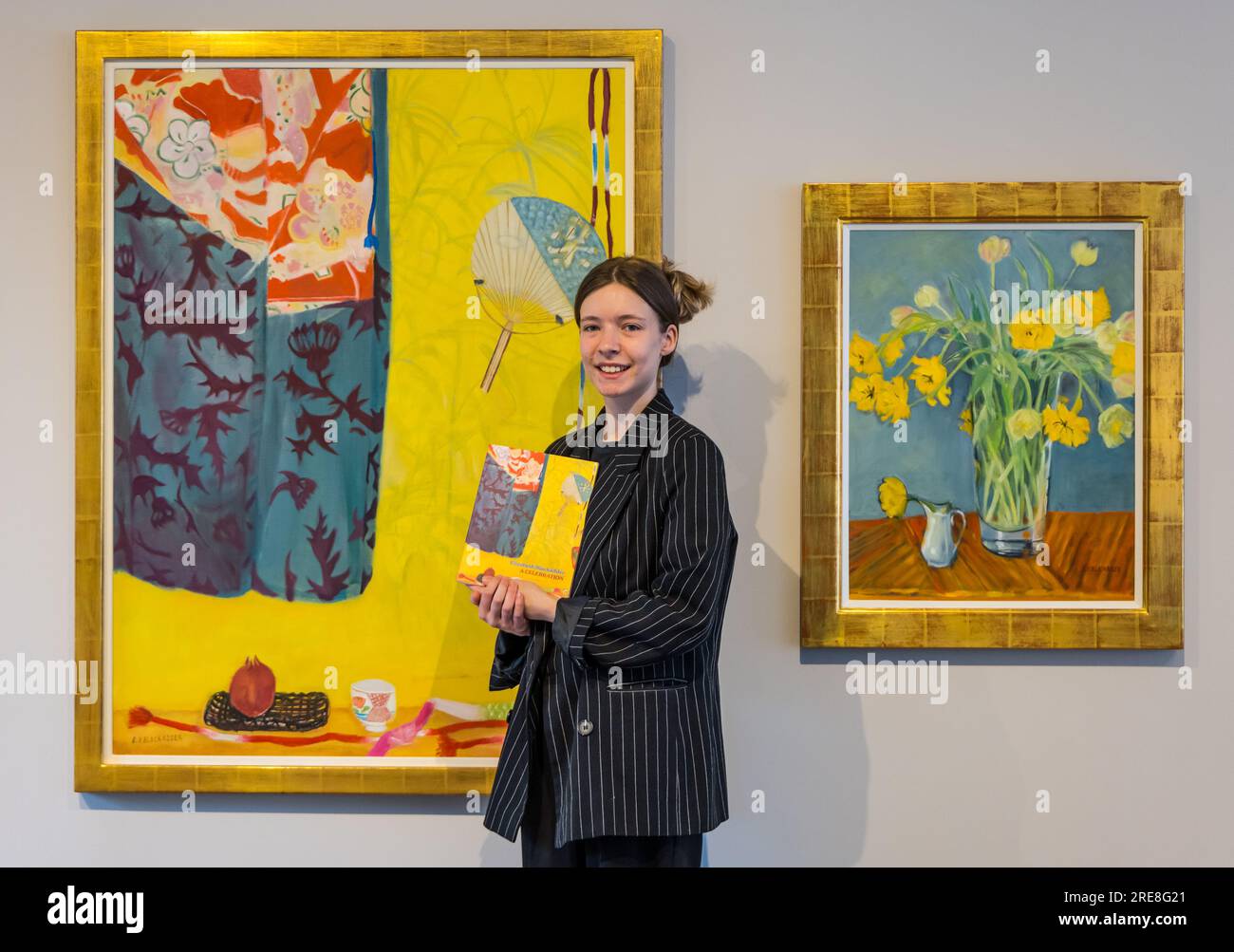 The Scottish Gallery, Edimburgo, Scozia, Regno Unito, 26 luglio 2023, Edinburgh Art Festival: Una nuova mostra chiamata Wonder Women presenta opere dell'artista di fama internazionale Dame Elizabeth Blackadder come parte dell'Edinburgh Art Festival. Nella foto: Un membro dello staff della galleria con dipinti di Elizabeth Blackadder e il catalogo della mostra. Crediti: Sally Anderson/Alamy Live News Foto Stock