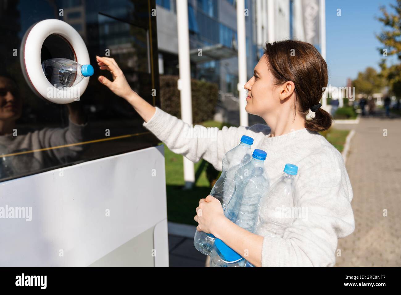 La donna usa una macchina self-service per ricevere bottiglie e lattine di plastica usate in una strada cittadina. Foto Stock