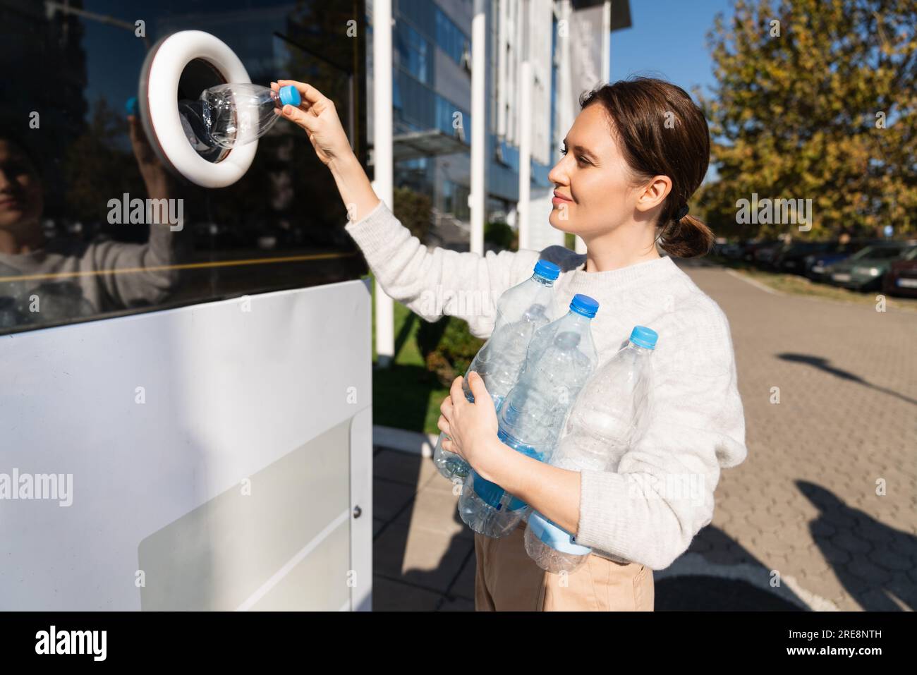 La donna usa una macchina self-service per ricevere bottiglie e lattine di plastica usate in una strada cittadina. Foto Stock