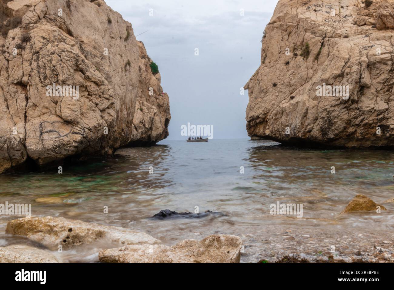 Una barca su una spiaggia tra due grandi montagne rocciose, in una delle spiagge di Jebha, in Marocco Foto Stock