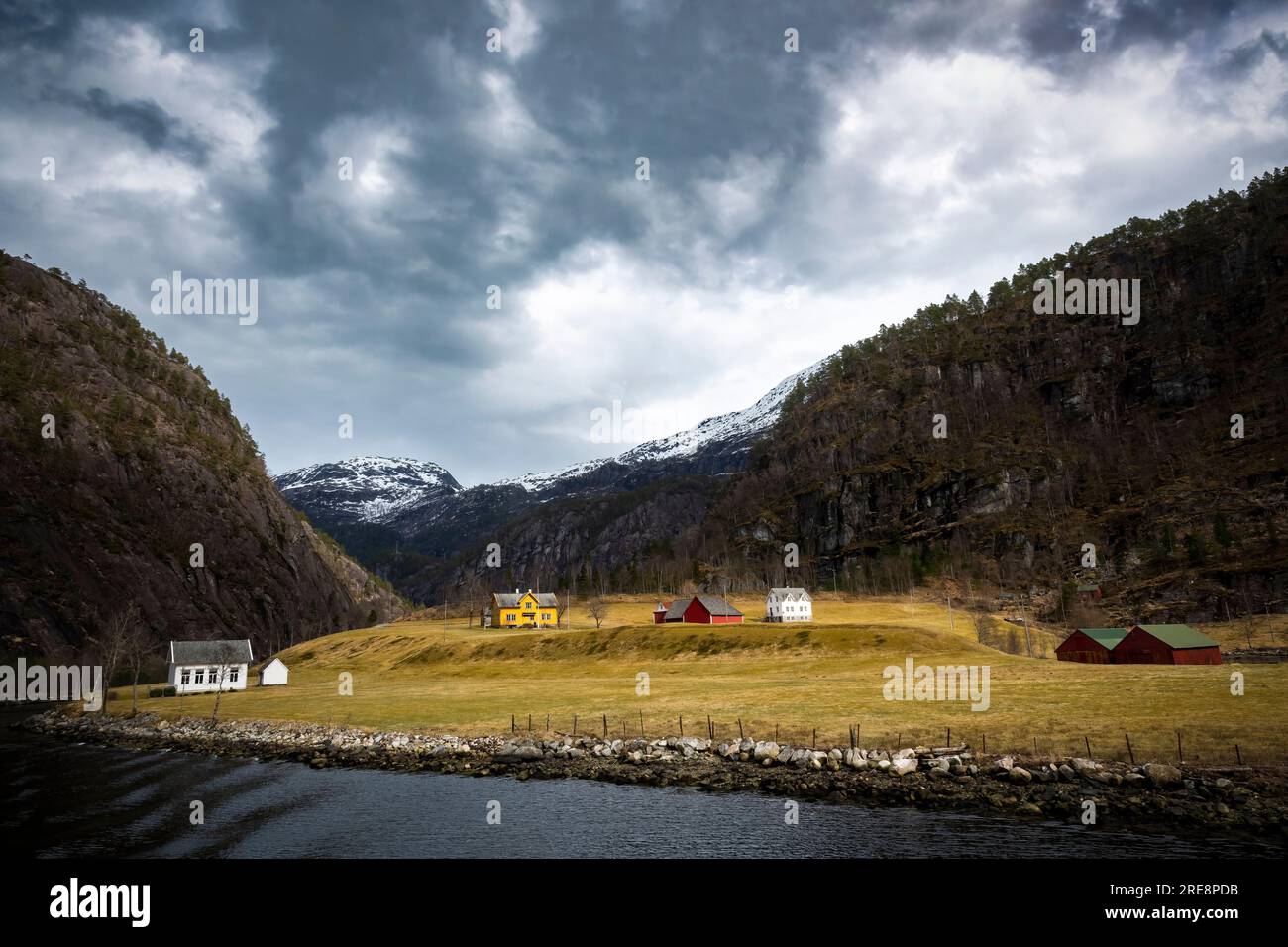 Edifici tradizionali in fiordo norvegese circondati da ripidi lati Foto Stock