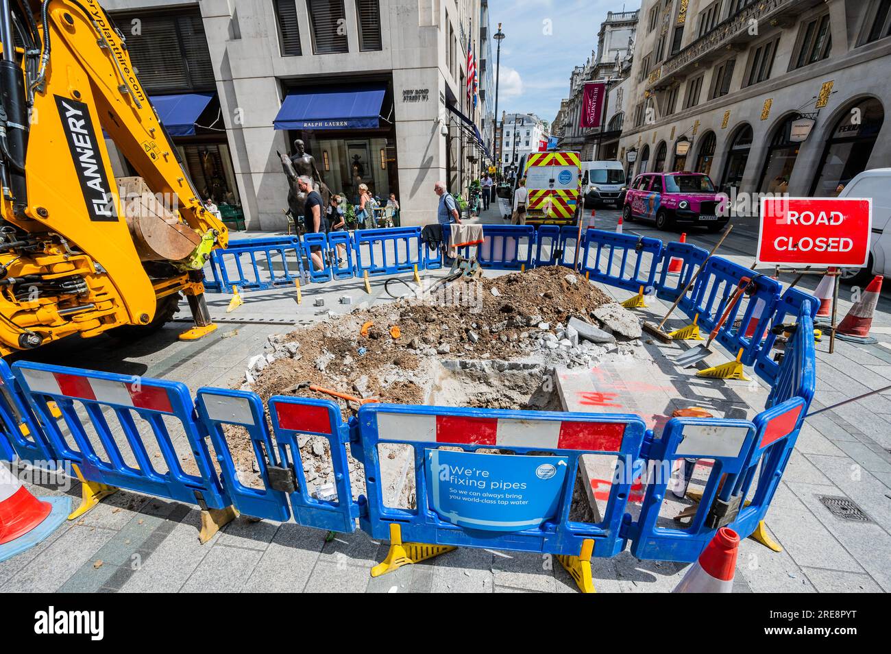 Londra, Regno Unito. 26 luglio 2023. Stiamo riparando tubi dice il cartello sulla recinzione intorno a un buco scavato da Thames Water in Old Bond Street. La mancanza di attività è una metafora dei problemi dell'azienda e dei lenti progressi nella riparazione delle perdite. Crediti: Guy Bell/Alamy Live News Foto Stock