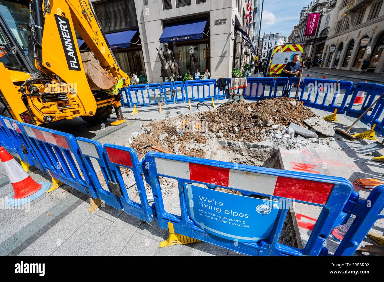 Londra, Regno Unito. 26 luglio 2023. Stiamo riparando tubi dice il cartello sulla recinzione intorno a un buco scavato da Thames Water in Old Bond Street. La mancanza di attività è una metafora dei problemi dell'azienda e dei lenti progressi nella riparazione delle perdite. Crediti: Guy Bell/Alamy Live News Foto Stock