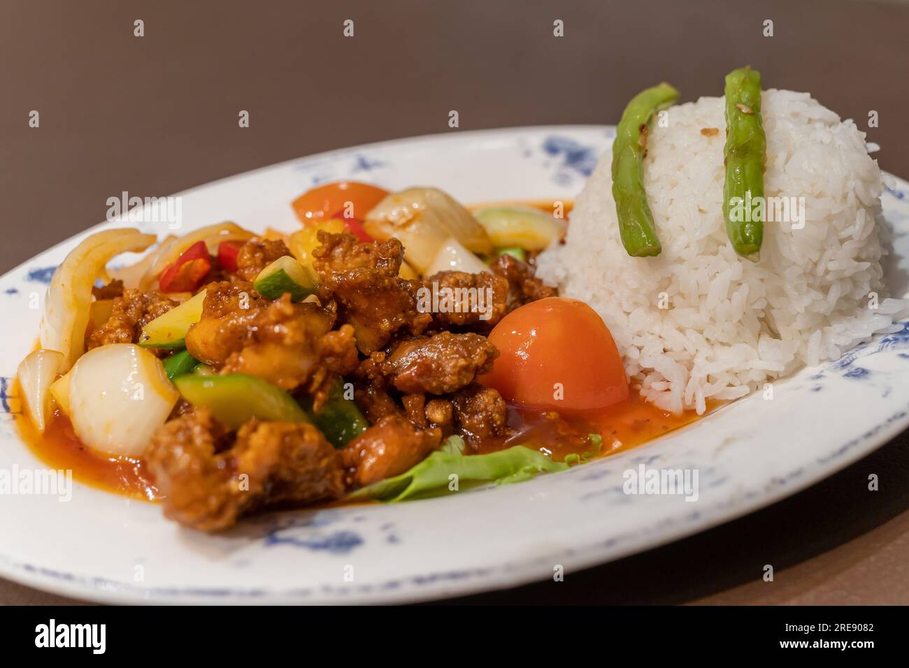 Maiale agrodolce con riso e verdure sul piatto Foto Stock