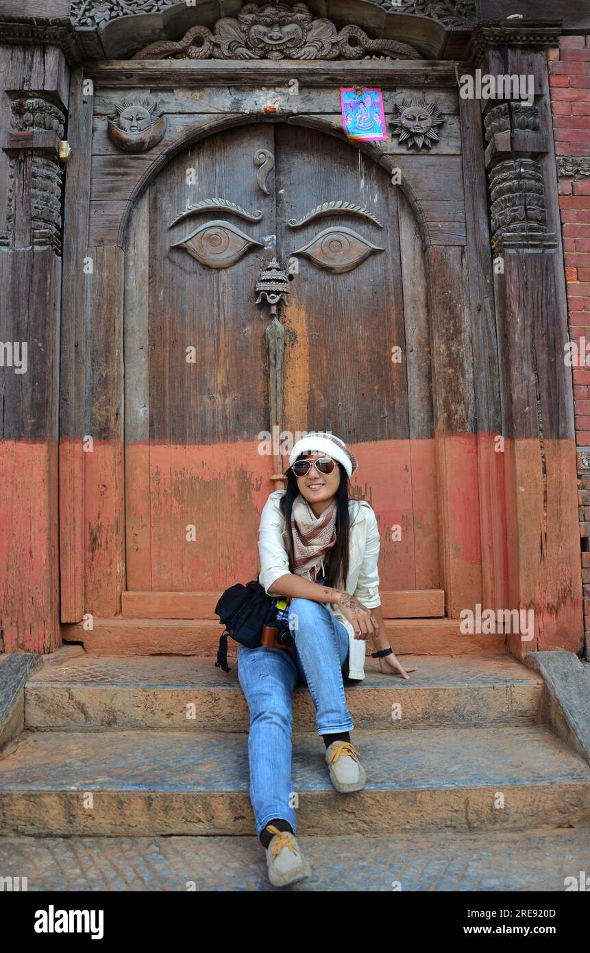 Le donne thailandesi viaggiano e viaggiano per visitare gli antichi occhi d'arte della saggezza buddha su antiche porte in legno nell'architettura nepalese e rovine della pala reale Foto Stock