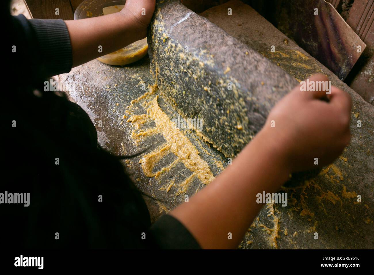 Preparazione del peperoncino giallo peruviano, chiamato anche salsa aji amarillo con un mulino nella città di Cusco in Perù. Foto Stock