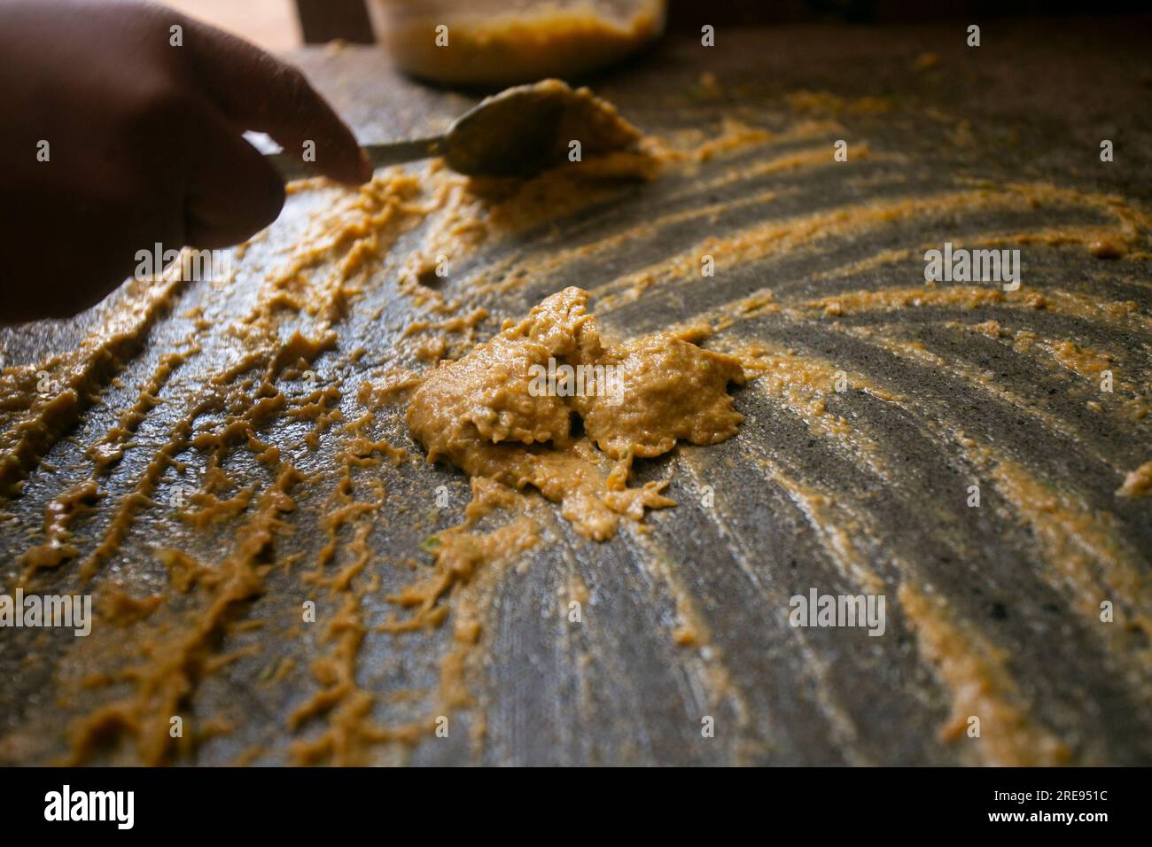 Preparazione del peperoncino giallo peruviano, chiamato anche salsa aji amarillo con un mulino nella città di Cusco in Perù. Foto Stock