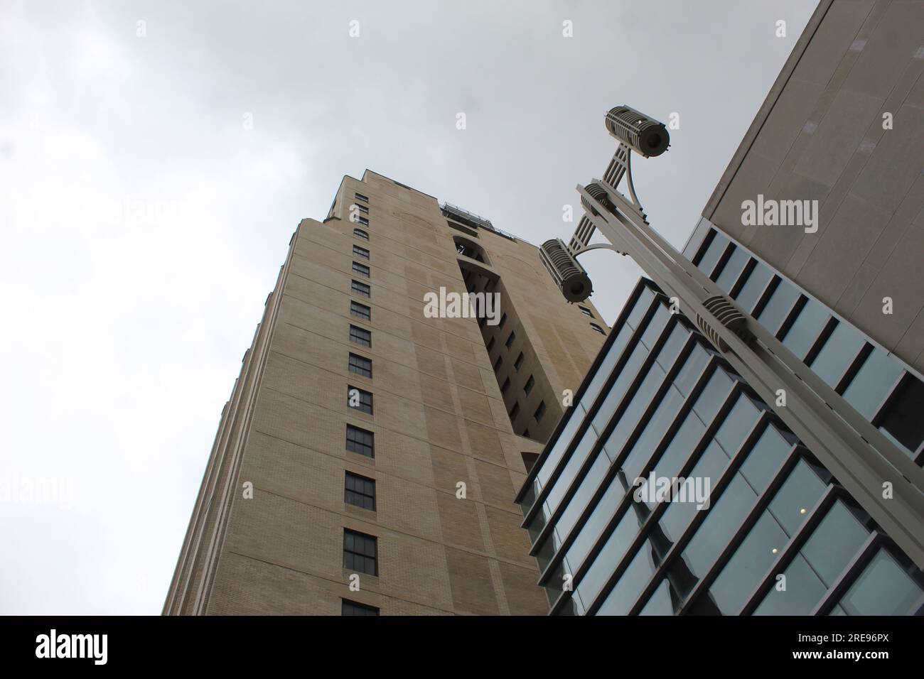 Una foto dall'angolo verso l'alto di un lampione stradale e di un grande edificio alto contro un cielo grigio nuvoloso a Philadelphia, Stati Uniti. Foto Stock