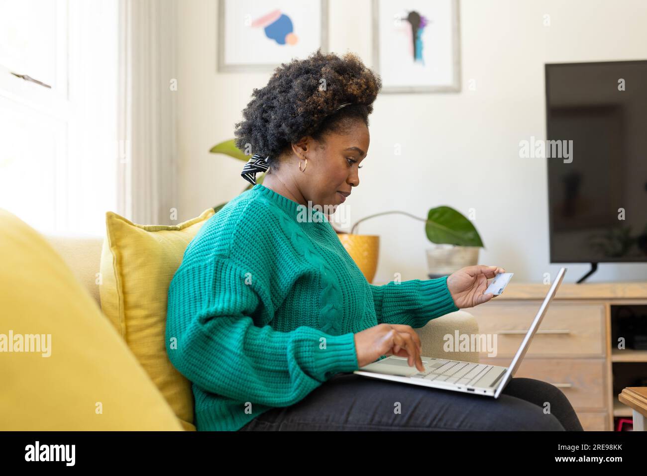 Donna afro-americana più grande che usa un computer portatile e una carta di credito a casa Foto Stock