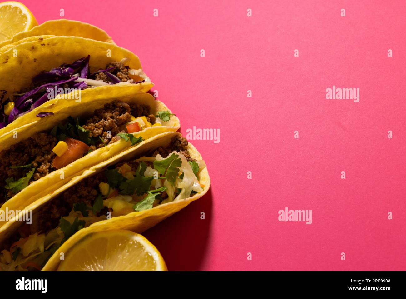Vista ad angolo elevato dei tacos con fette di limone su sfondo rosa, spazio di copia Foto Stock