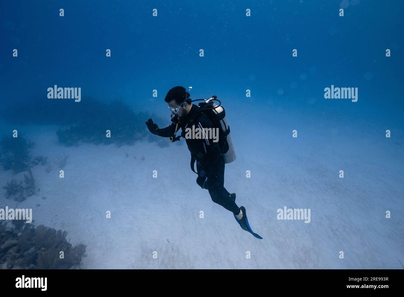 Vista laterale del subacqueo che nuota sott'acqua con le bolle e guarda in basso mentre esplori il mare cristallino durante il tour subacqueo a Cancun Foto Stock