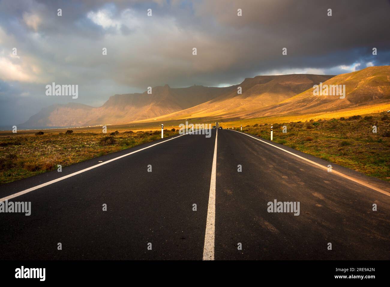 Una strada panoramica conduce direttamente a el Risco de Famara durante l'ora d'oro Foto Stock