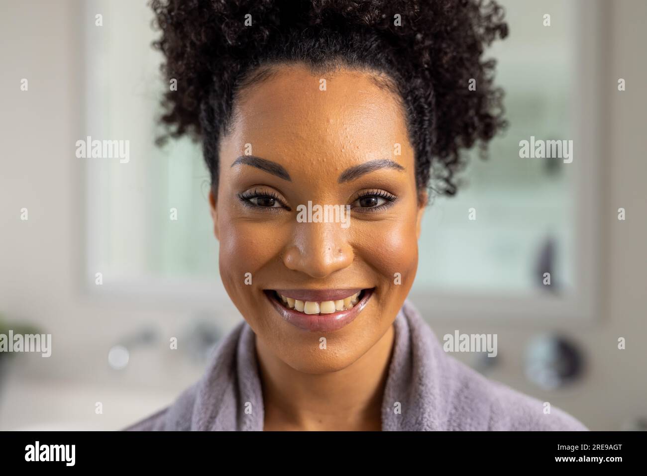 Ritratto della donna birazziale felice in accappatoio in bagno Foto Stock