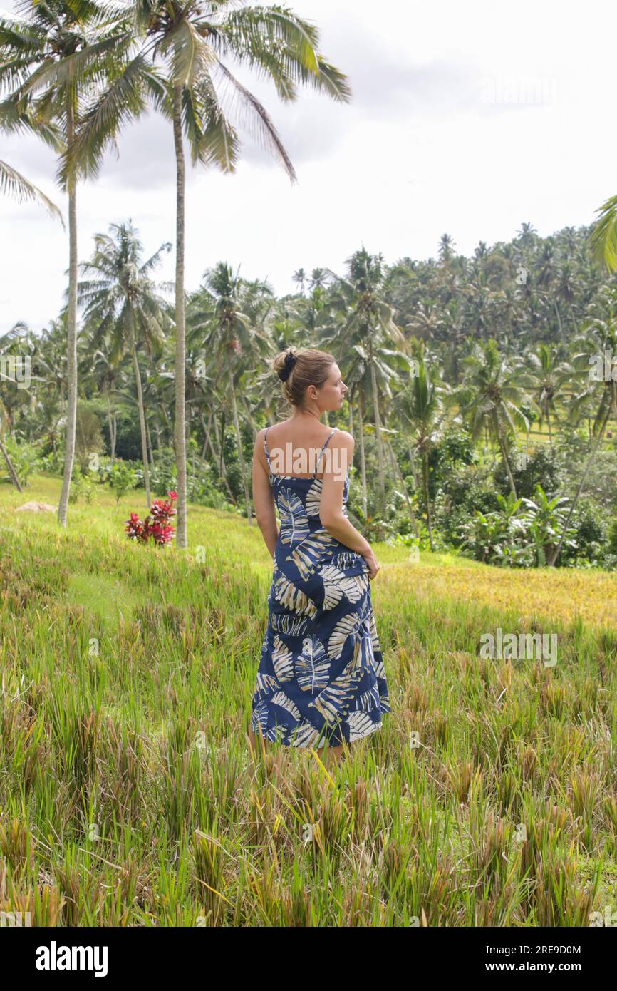 Ritratto di moda all'aperto di una giovane donna nella risaia dell'isola tropicale con bellissime palme da cocco e luce naturale del sole. Concetto di Freedo Foto Stock