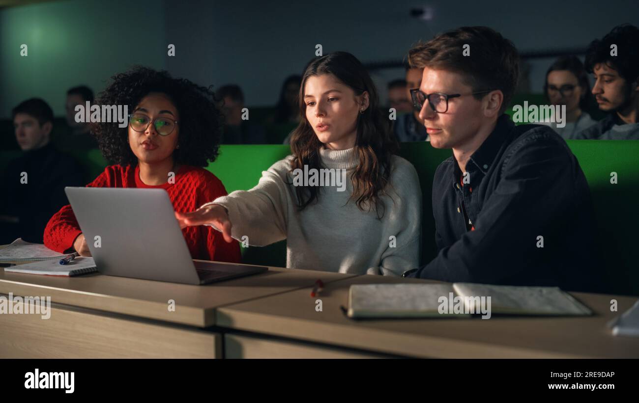 Giovani studenti intelligenti che studiano all'università con diversi compagni di classe multietnici. Gli studiosi hanno una conversazione in College Room. Applicazione delle conoscenze Foto Stock