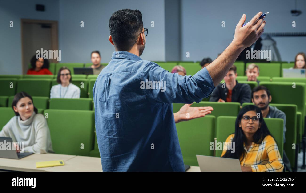 Insegnante che tiene una lezione a un gruppo multietnico eterogeneo di studenti femminili e maschili nella moderna sala del Collegio. Studiosi curiosi e premurosi che studiano Foto Stock